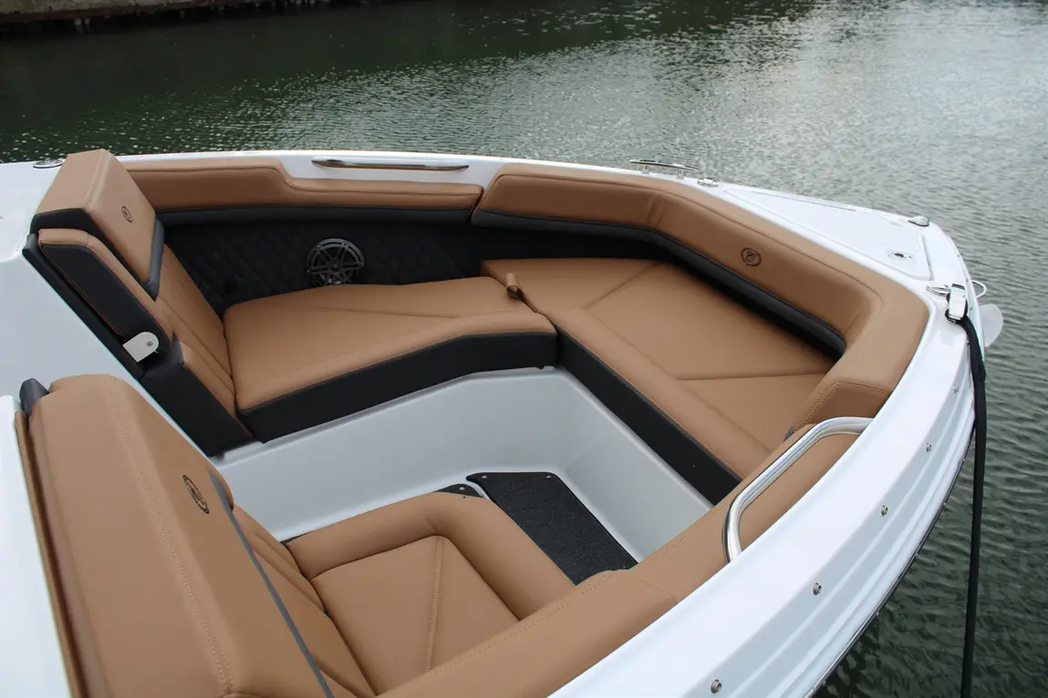 Luxury boat interior featuring tan and black seating, a sleek design, and a view of calm water.